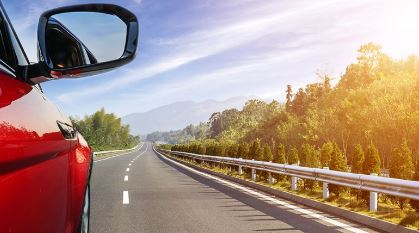 A car drives down a tree lined road